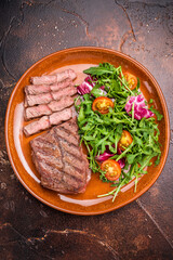 Grilled Australian Oyster Top blade steak with salad on a plate. brown background. top view