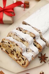 Cut traditional Stollen cake, gift and Christmas decor on white table, flat lay