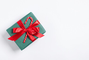 Decorated Christmas gift with candy cane on white background, top view. Space for text