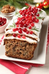 Tasty Christmas cake with icing, cranberries and rosemary on white wooden table, closeup