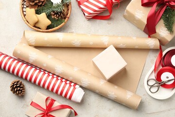 Festive packaging. Gift boxes, wrapping paper, Christmas decor, ribbon and scissors on light textured table, flat lay