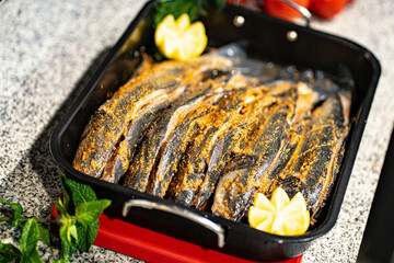Fish fresh marinated fish with sweet onions, lemon and rosemarin in oven tray and baking paper ready to cook