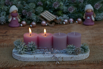 Second Advent: Advent arrangement with pink candles, Christmas decorations and small dolls.