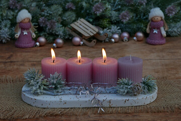 Third Advent: Advent arrangement with pink candles, Christmas decorations and small dolls.