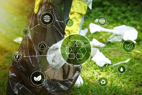 Woman with plastic bag picking up garbage on green grass outdoors, closeup. Scheme with recycling symbol and different icons. Ecology and clean environment