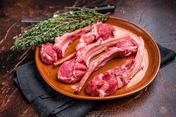 Uncooked lamb chops, fresh mutton meat steaks on a plate. brown background. top view