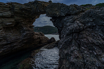 Dark sea arch in rugged coastal cliffs