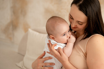a mother holds a newborn baby in her arms, a mother gently hugs and kisses a small child, maternal love and care, a mom and a baby