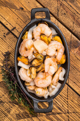 Ready for cooking fresh Raw Seafood Cocktail with Mussels, Clams, Prawns, Shrimps and squid in skillet. wooden background. top view