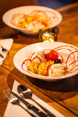 split ice cream with syrup and strawberry on white plate, side view. Chocolate, strawberry and vanilla ice cream scoops on plate, summer dessert Vertical