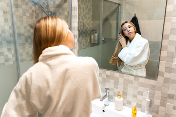 Young woman doing hair care in bathroom