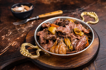 Slow cooked Beef Cheek, Braised meat with vegetables in a skillet. brown background. top view