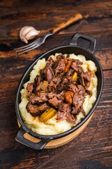 Braised Beef Cheek, Slow cooked meat with smashed potatoes in a skillet. wooden background. top view