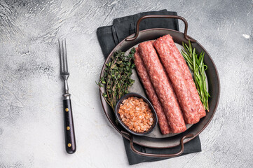 Raw Cevapcici ready for the grill, fresh Cevapi from mince beef meat. grey background. top view