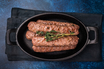 Grilled Cevapcici Sausage, roasted Cevapi from mince beef and pork meat in a skillet. blue background. top view
