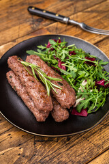 Balkan BBQ roast Cevapcici Sausage, roasted Cevapi from mince beef and pork meat. wooden background. top view