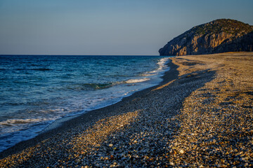 Pebble beach and rocky headland in warm evening light