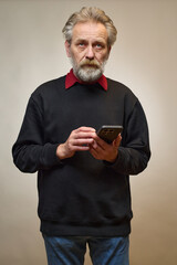 Old man over 60 portrait in studio with smartphone
