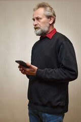 Old man over 60 portrait in studio with smartphone