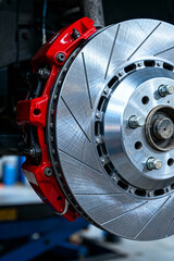 Red brake caliper and rotor close-up in automotive service workshop during routine inspection and maintenance