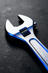 Close-up of a metallic adjustable wrench with a shiny finish resting on a dark surface in an automotive service setting