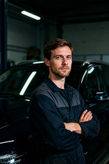 Skilled automotive technician standing confidently with arms crossed in service garage