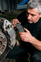 Experienced mechanic works on brake system in automotive service shop during daytime