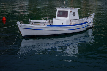 Fototapeta premium Small white fishing boat moored on calm water