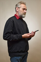 Old man over 60 portrait in studio with smartphone