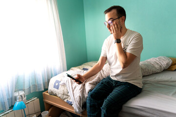 Fototapeta premium Freelance programmer man waking up checking smartphone in bed