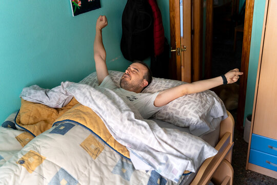 Man waking up morning stretching in bed at home