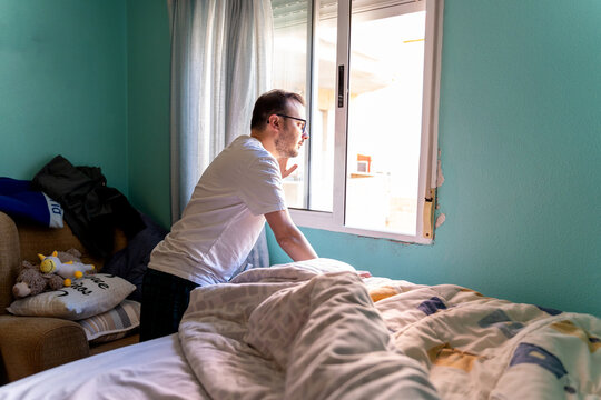 Man waking up looking out bedroom window