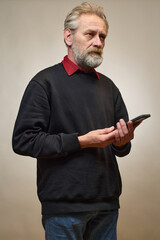 Old man over 60 portrait in studio with smartphone