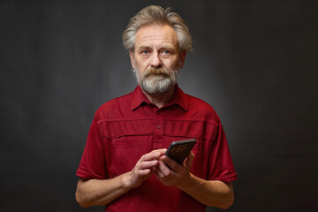 Old man over 60 portrait in studio with smartphone on black background