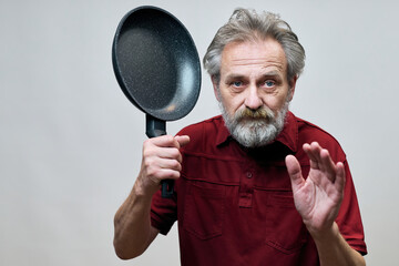 Older man with wrinkles on face skin posing as aggressor in studio