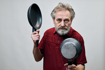 Older man with wrinkles on face skin posing as aggressor in studio