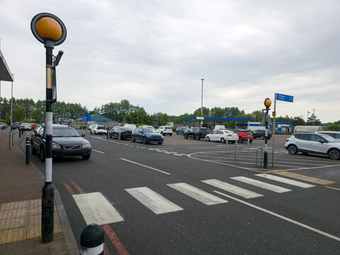Belisha beacon, which is a flashing amber light used to mark pedestrian crossings in the UK. Crossing the road in a shopping center parking lot. To alert drivers to the presence of a crossing. 