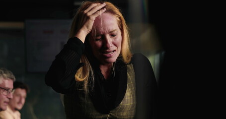 Blonde businesswoman in visible emotional breakdown during office meeting, holding head with both...