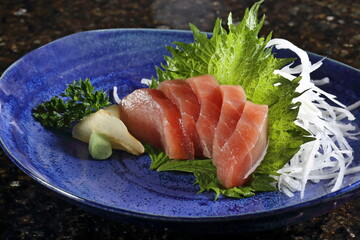 Tuna sashimi with greens on a plate