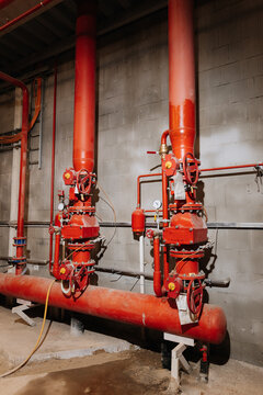Fire sprinkler valves and red pipes in industrial plant, safety equipment, vertical view