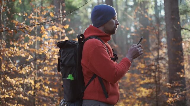 Outdoor mapping in hike. Man hiker uses smartphone to navigate in forest using an application and digital maps. Route for hiking in smart phone. Traveler guides in woods by GPS. Travel and explore. 