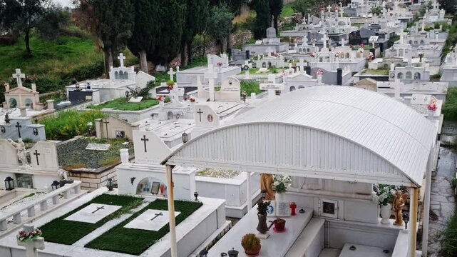 An 4K cinematic view of a marble cemetery featuring rows of tombstones, crosses, and decorated memorials