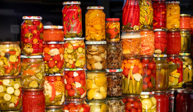 Colorful jars of pickled vegetables stacked at market stall showcasing homemade canning and variety