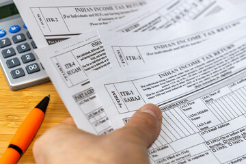 India taxes. Concept of finance and business. Financial settlements with the Indian government. Various tax forms in hand. Calculator and pen on the desk. Tax refund.