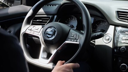 Male arms holds steering wheel while driving a motor car at city. Young man operating the automobile at urban road. Driver moving in his auto on route. Slow motion