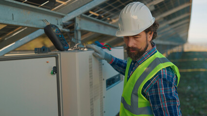 Technician inspecting solar power equipment in a renewable energy facility during daylight hours