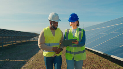 Professionals review solar panel installation progress at a renewable energy site in bright daylight