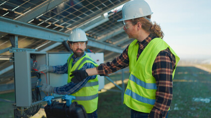 Workers performing maintenance on solar panels during a sunny day in a rural area