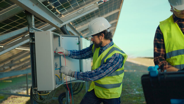 Technicians working on solar panel installation in a clear blue sky during the day - Powered by Adobe