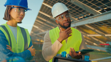 Engineers discussing solar panel installation at a renewable energy site during daylight hours